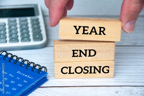 Year end closing text on wooden blocks with December calendar, glasses and pen. Accounting and year end closing concept.