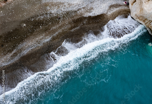 Drone aerial of rocky coast with sea waves hitting the shore. Seascape from above. photo
