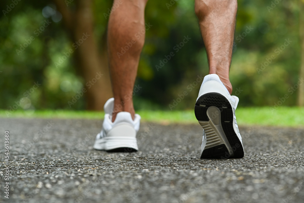 Close up view of strong athletic legs of sport man jogging running on the road. Fitness, sport and healthy lifestyle concept