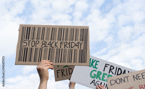 Protesters holding signs with slogans Stop Black Friday, Make Friday Green Again. People with placards at zero waste protest rally. Ecology environmental issues, demonstration against overproduction.