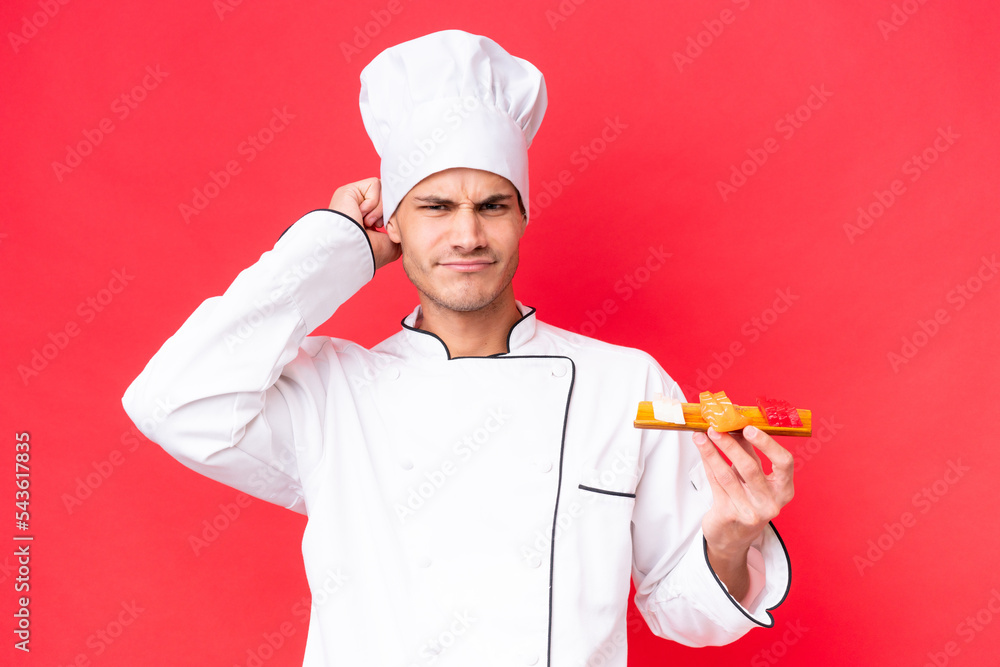 Young caucasian chef man holding sashimi isolated on red background having doubts Young caucasian chef man holding sashimi isolated on red background having doubts