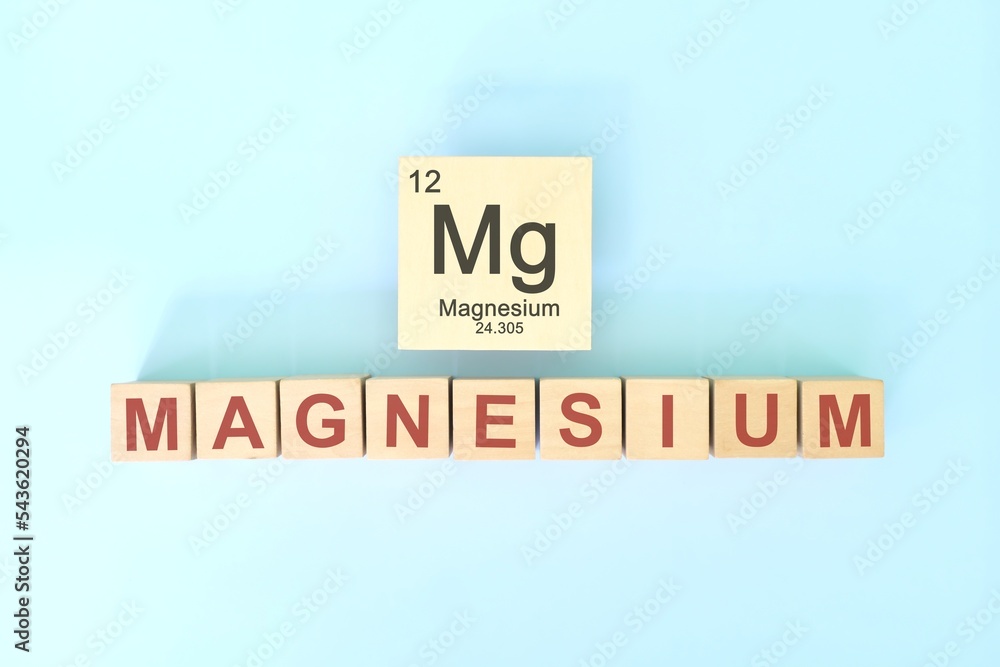 Magnesium chemical element symbol with atomic mass and atomic number in wooden blocks flat lay composition. Chemistry and Science concept.