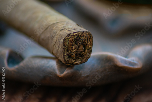 Closeup photo of a cigar on a clay ashtray