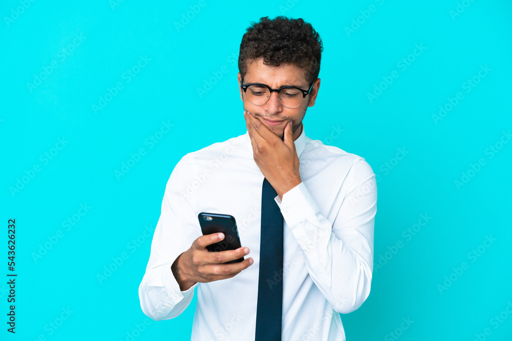Young business Brazilian man isolated on blue background thinking and sending a message Young business Brazilian man isolated on blue background thinking and sending a message