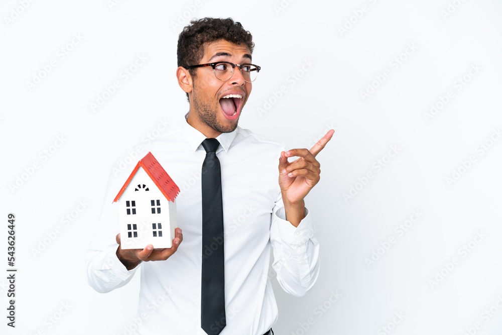 Young business Brazilian man holding a house toy isolated on white background intending to realizes the solution while lifting a finger up Young business Brazilian man holding a house toy isolated on white background intending to realizes the solution while lifting a finger up