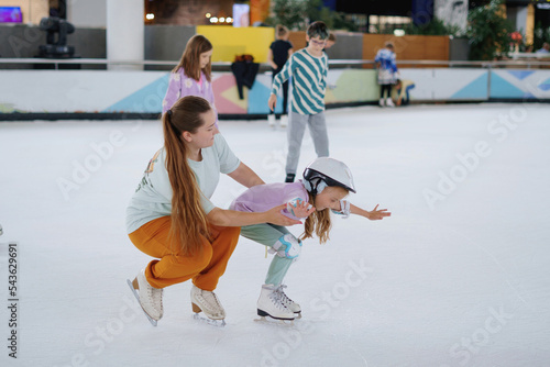 oman teaches a girl figure skating on ice.