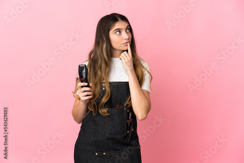 Young hairdresser woman isolated on pink background having doubts while looking up