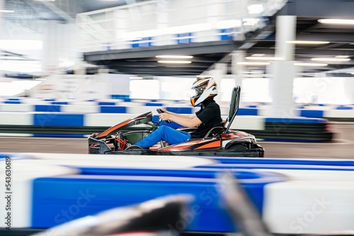teenager in a racing helmet races a go-kart on a go-kart track