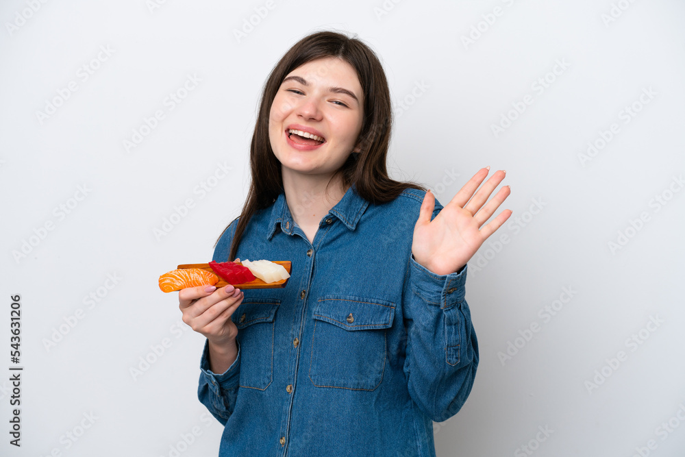 Young Russian woman holding sashimi isolated on white background saluting with hand with happy expression Young Russian woman holding sashimi isolated on white background saluting with hand with happy expression