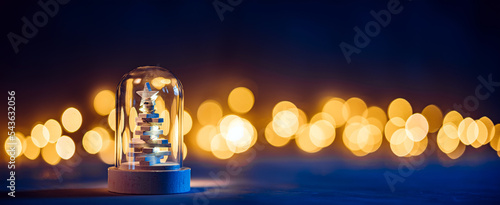 Fotografiet A small wooden Christmas tree in a glass dome in the winter night darkness on th