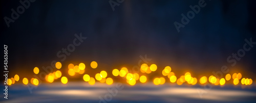 Christmas blurred texture background with bokeh lights and light reflections on snow