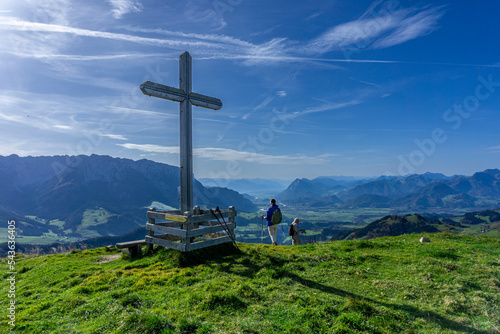 Wandern in Tirol Nähe Walchsee: Die Berge vom Zahmen und der Wilden Kaiser - Blick vom Gipfelkreuz Brennköpfl Richtung Inntal mit zwei Wanderern