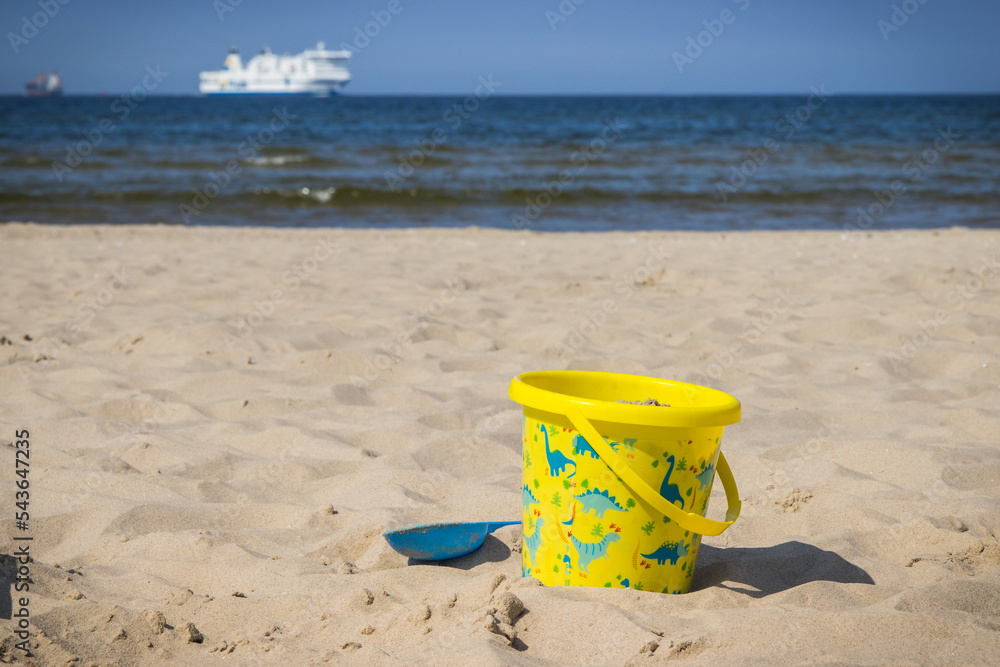 Children toys for relax or playing on sand at beach. Vacation time. Passengers ferry in background Children toys for relax or playing on sand at beach. Vacation time. Passengers ferry in background