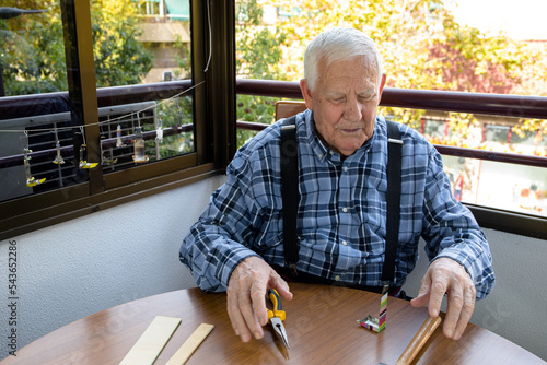 90 year old grandfather working at home, making oil lamps with his tools