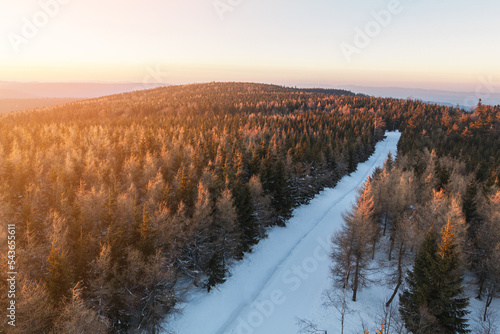 Sunset over Orlické hory (Eagle mountines) from Poland side in Jagodna. Forest and road covered in snow. photo