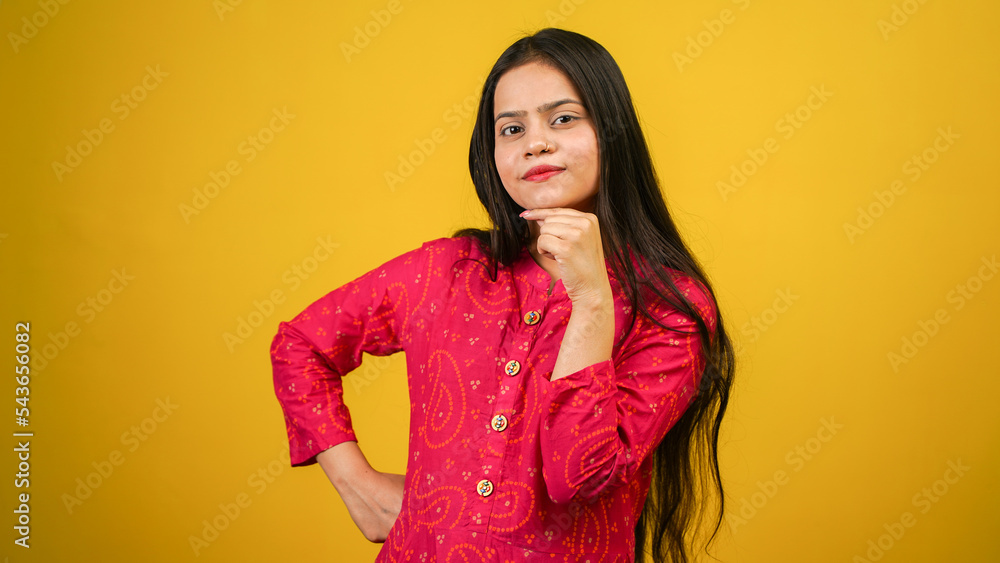 Pretty young woman looking up empty space deep thinking, holding arm on chin, isolated over yellow color background Pretty young woman looking up empty space deep thinking, holding arm on chin, isolated over yellow color background