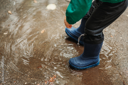 Boy feet in rubber boots while playing outside on a rainy day