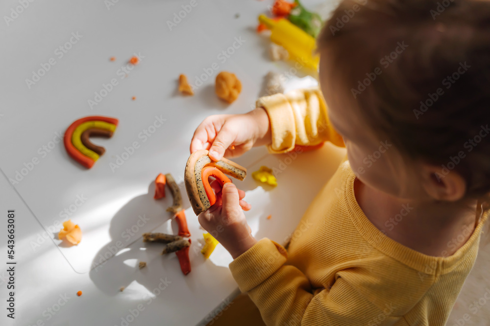 Foto de A little girl playing with rainbow from play dough for modeling. Art Activity for Kids