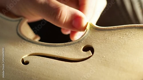violinmaker sanding violin shapes border edgework of blank unpainted instrument