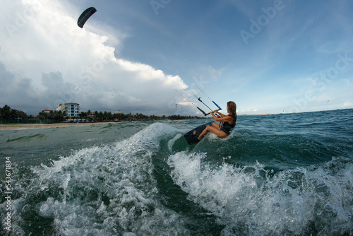 Female Kite surfer riding a kiteboard on the sea with splash.