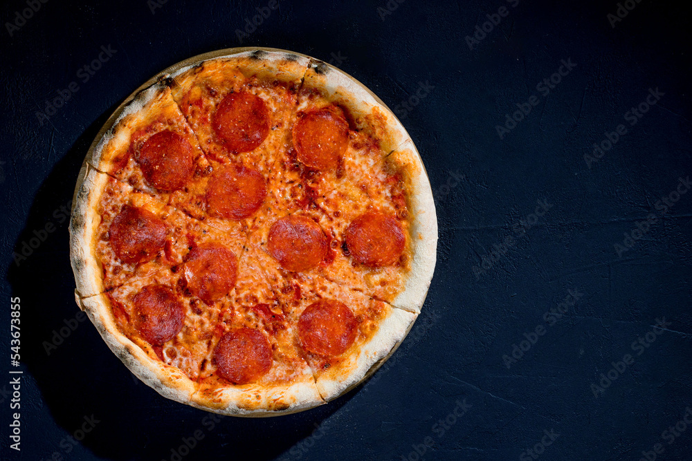 Pizza with tomato sauce, mozzarella, salami on black background. View from above, copy space Pizza with tomato sauce, mozzarella, salami on black background. View from above, copy space
