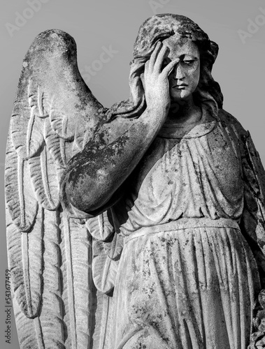 An ancient sculpture of a sad angel mourning the dead.