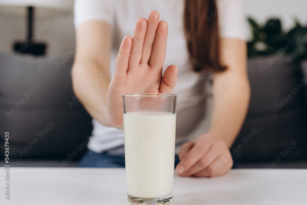 Lactose intolerance concept. Close up of young woman pushing glass of