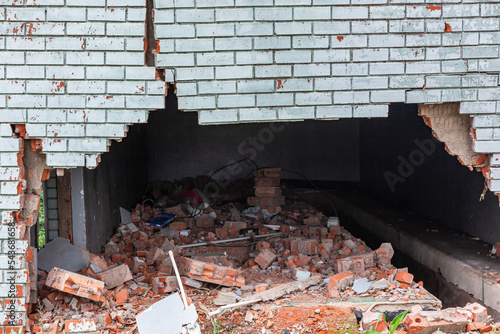 Building Exterior Wall Cracked Damaged red bricks blue paint structure dangers closeup photograph. photo