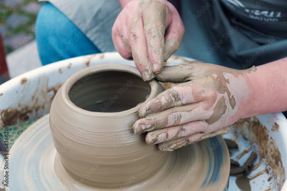 Close up hands working on pottery wheel and making a clay pot, selective focus