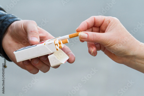 Smoking concept. Female hand take a cigarette from the pack in the male hand