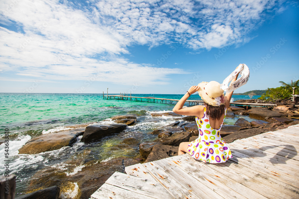 Young Asian lady tourist sitting on the wooden bridge in to the sea on her holiday, Trad province,Thailand. Young Asian lady tourist sitting on the wooden bridge in to the sea on her holiday, Trad province,Thailand.