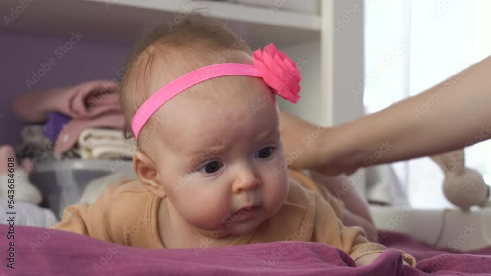 Close-up of cute baby girl with pink headband on head lying on stomach on changing table Close-up of cute baby girl with pink headband on head lying on stomach on changing table