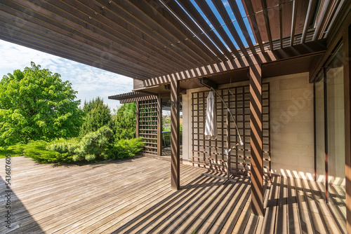 Wooden terrace with gazebo on a clear sunny day. View of the beautiful landscape of the courtyard. photo