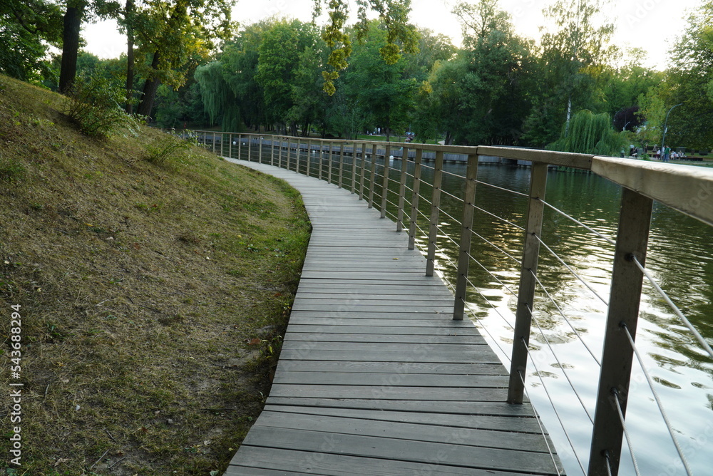 Moscow, Russia - August 29, 2022: Wooden path with railings along the park on the water, at VDNH