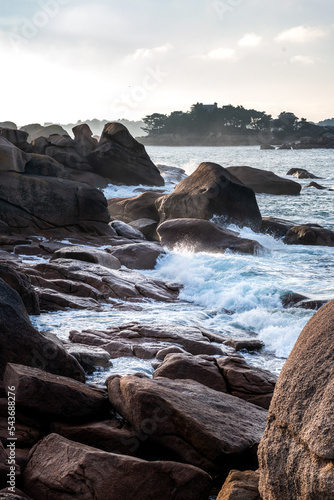 France, Ploumenach, 22022-01-13. Wave breaking on a rock formation along the pink granite coast in Brittany.