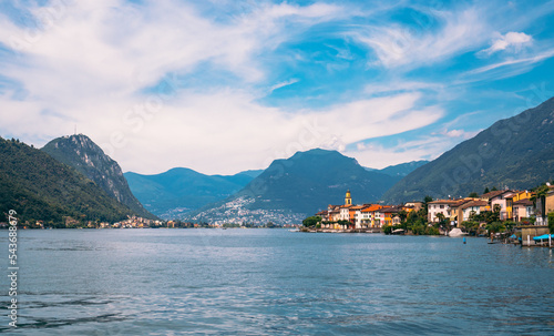 Panoramic view of Brusino Arsizio, located at the foot of Monte San Giorgio, on the shores of Lake Lugano, canton of Ticino, Switzerland. Beautiful landscape of the lake, Alps and lakeside villas.