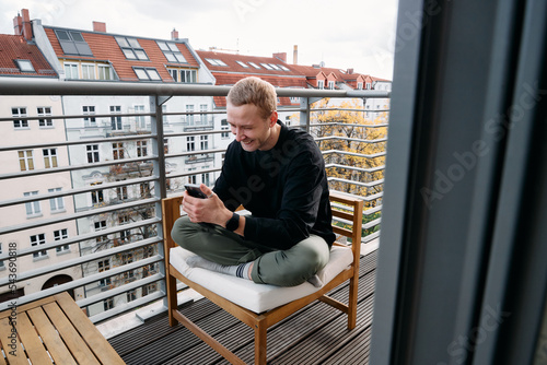 Wall Mural Young man sitting on the balcony talking to friends on the phone
