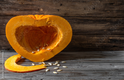 Half a pumpkin in the shape of a heart on an old wooden surface. Vegetarian food  and health concept