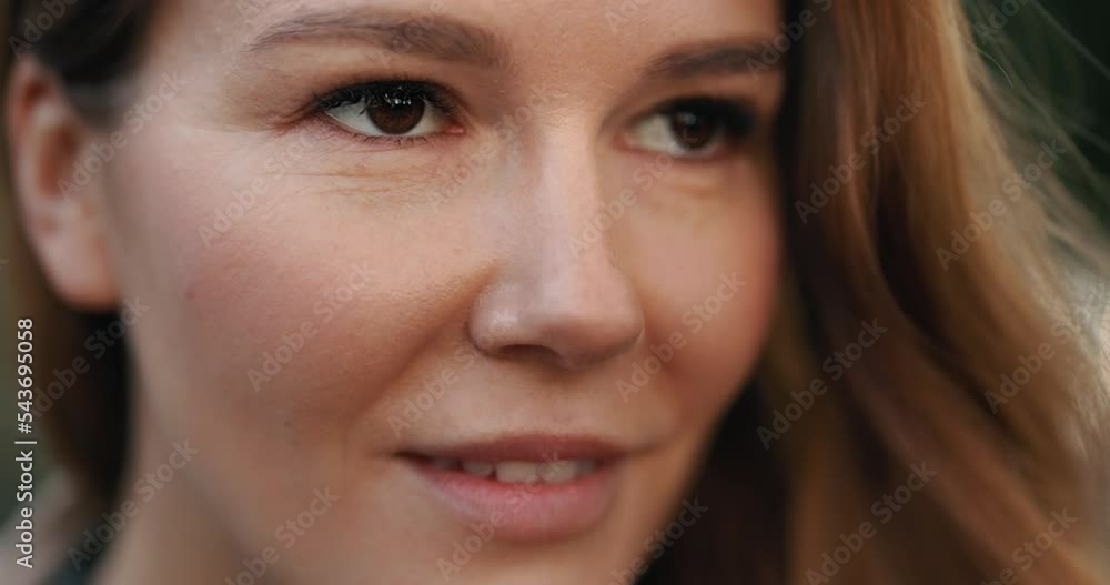 Close-up face of smiling woman with brown eyes looking ahead in slow motion Close-up face of smiling woman with brown eyes looking ahead in slow motion