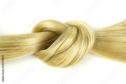 Blond natural hair on white background. Strand of honey blonde hair, top view. Lock of wavy hair on white background.