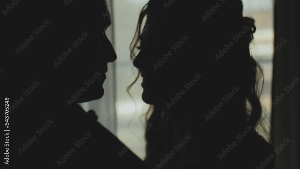 Silhouette of a man and woman in love kissing by the window, tenderness. Medium shot Silhouette of newlywed couple. Marriage, romantic atmosphere. Silhouette of a man and woman in love kissing by the window, tenderness. Medium shot Silhouette of newlywed couple. Marriage, romantic atmosphere.