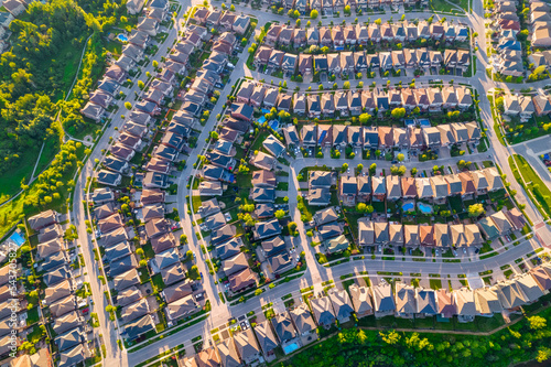 Aerial view of middle class residential houses at summer evening. American neighbourhood suburb. Residential houses and homes build in strong pattern to each other. Real estate.