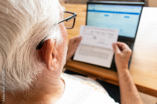 old senior male man sit table home notebook looking hold pay bills no money worry