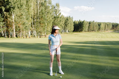 A woman plays golf on a green field in a golf club. Makes a kick to the ball. High quality photo
