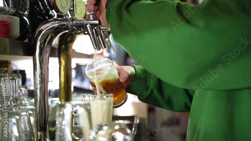 Bearded barman pooring beer from a tap in slow motion