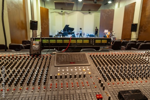 Big mixing console with many knobs with a concert hall and a stage in the background photo