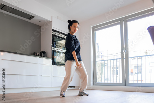 Excited active woman dancing to hip hop music in the studio kitchen