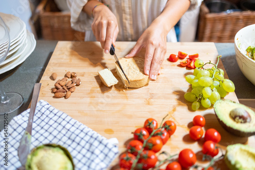 Female hands cutting slices of almond vegan cheese for breakfast