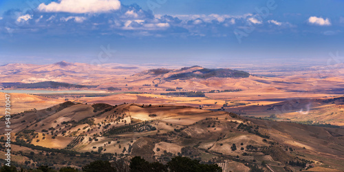 Wide angle view of the vast panorama of cultivated fields, productive settlements, hills and sea, taken from the archaeological site of Morgantina in Sicily