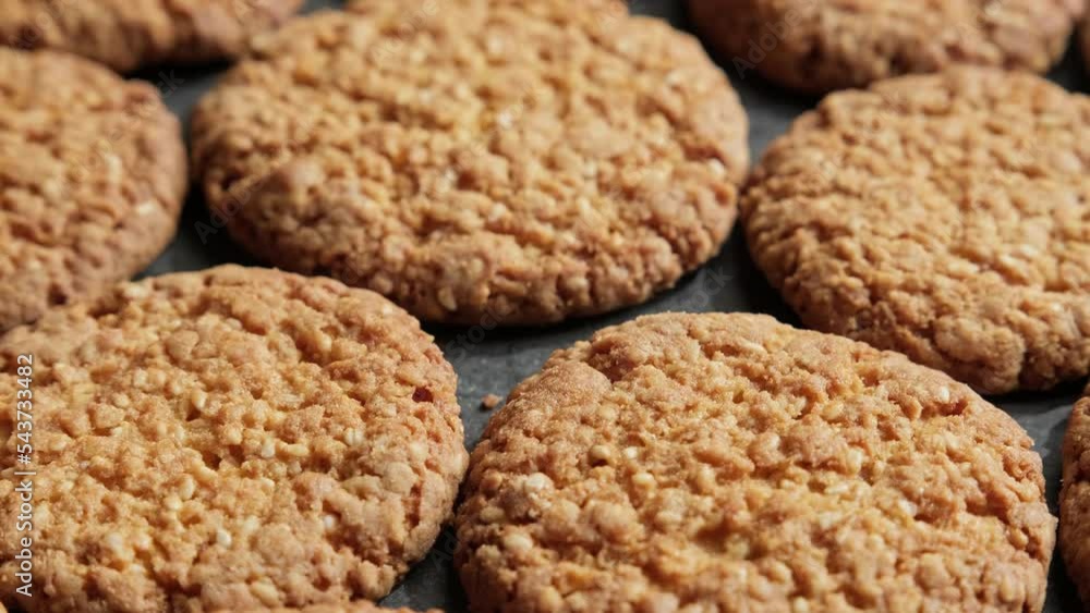Cookies with sesame seeds on dark plate. Top view of rotating fresh homemade cookies. Group of tasty oatmeal cookies. Food concept. 4K, UHD Cookies with sesame seeds on dark plate. Top view of rotating fresh homemade cookies. Group of tasty oatmeal cookies. Food concept. 4K, UHD